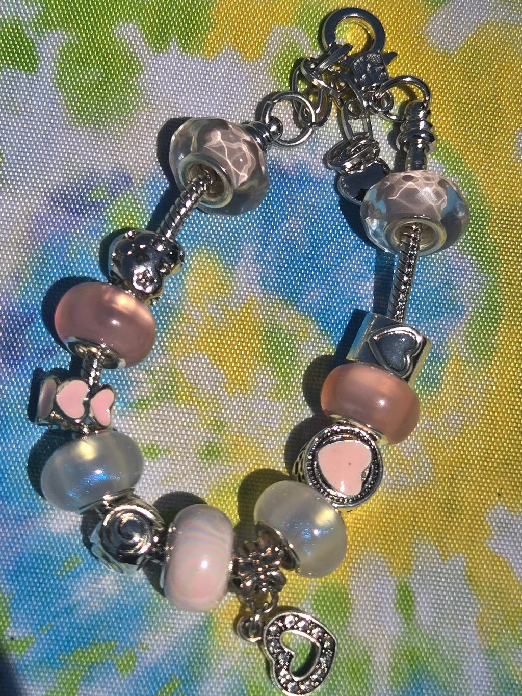 Bracelet with various charms on a colorful fabric background
