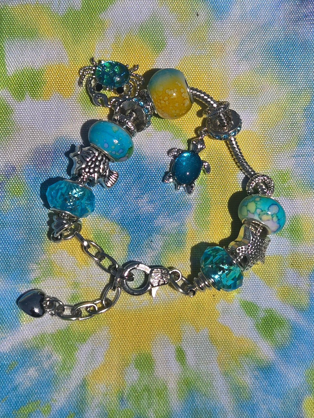 Bracelet with turtle charms and blue beads on a tie-dye background