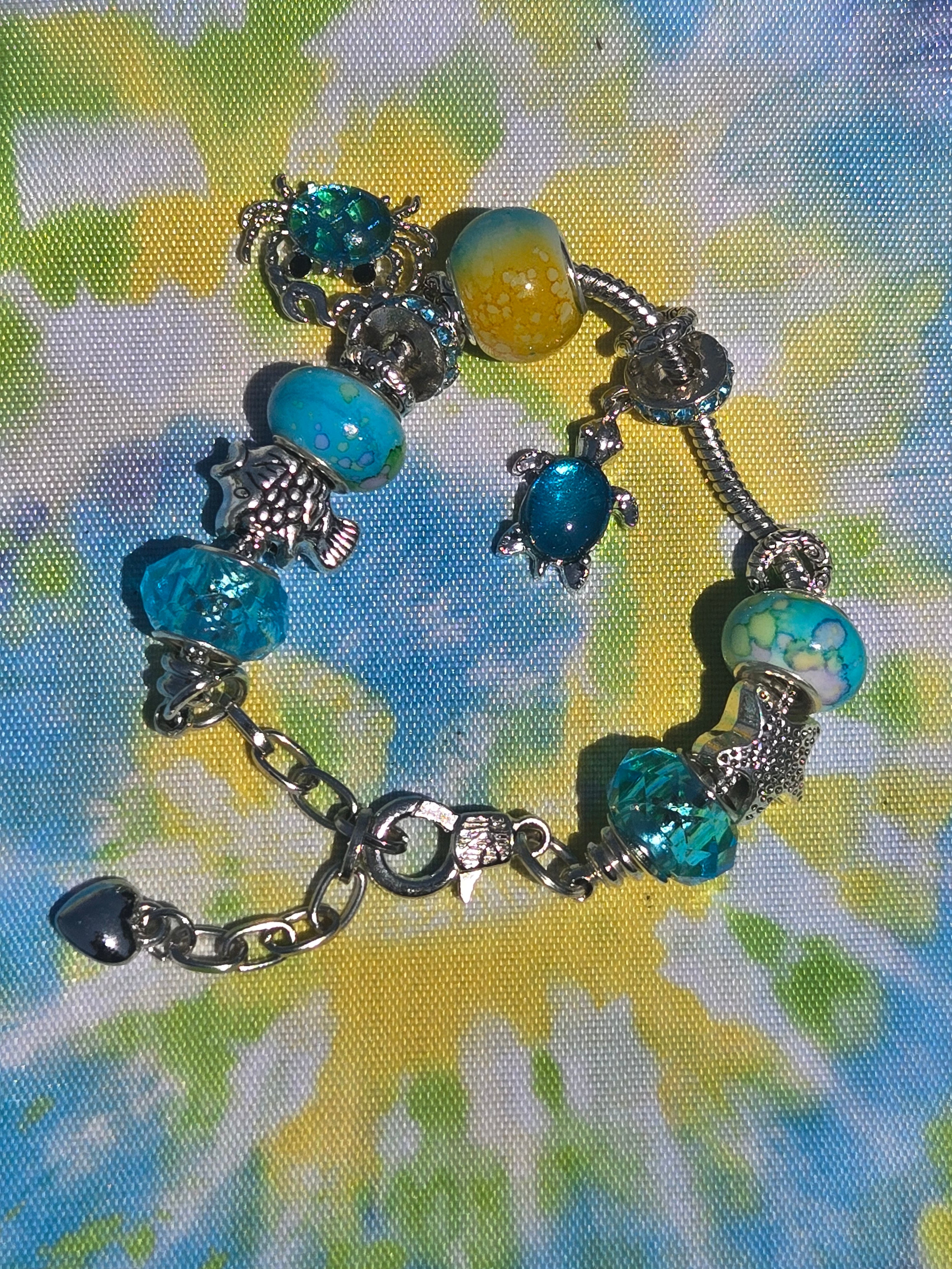 Bracelet with turtle charms and blue beads on a tie-dye background